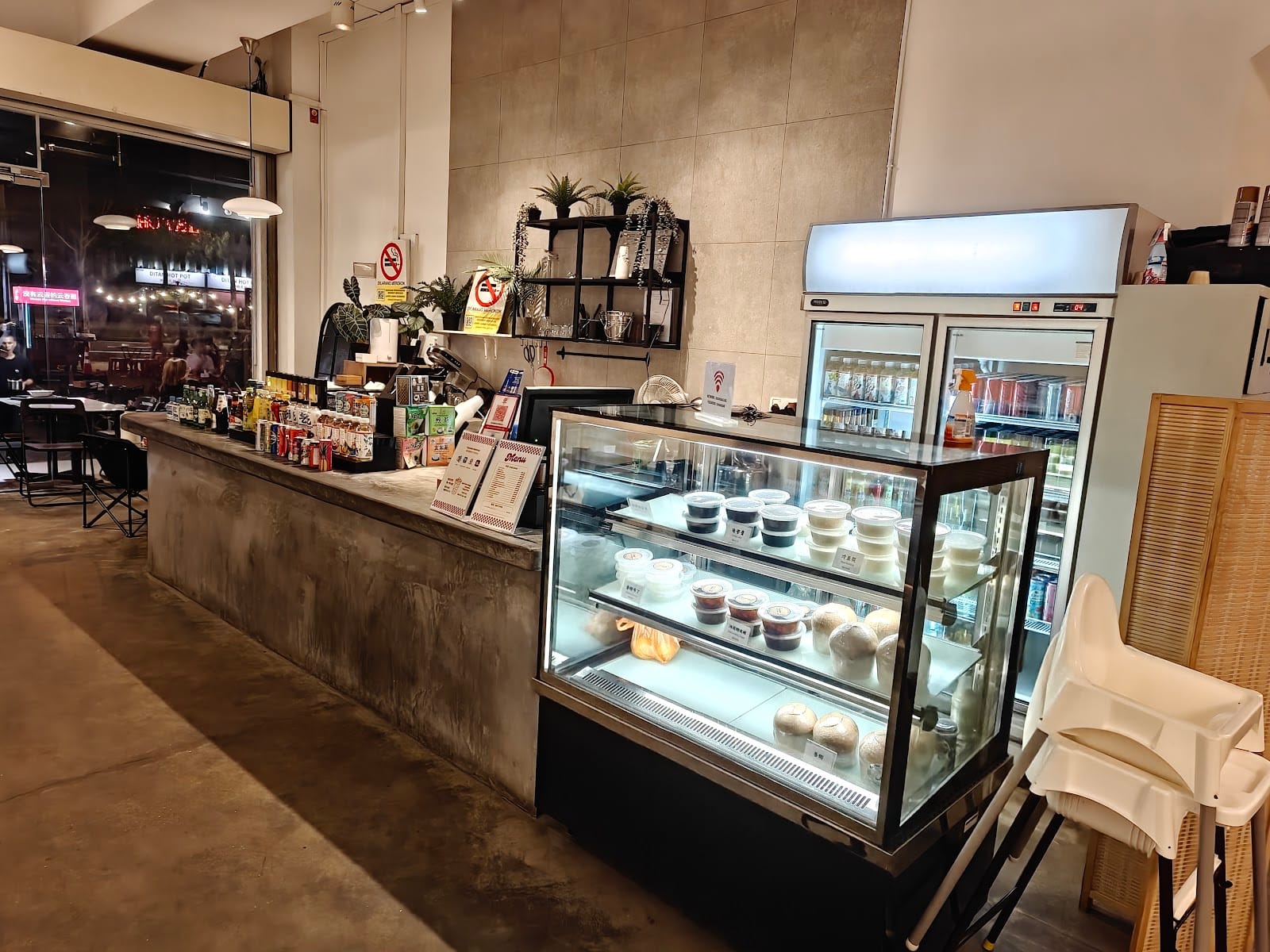 Inside Broloklok: a concrete drinks counter, a lit chiller cabinet and drinks fridges