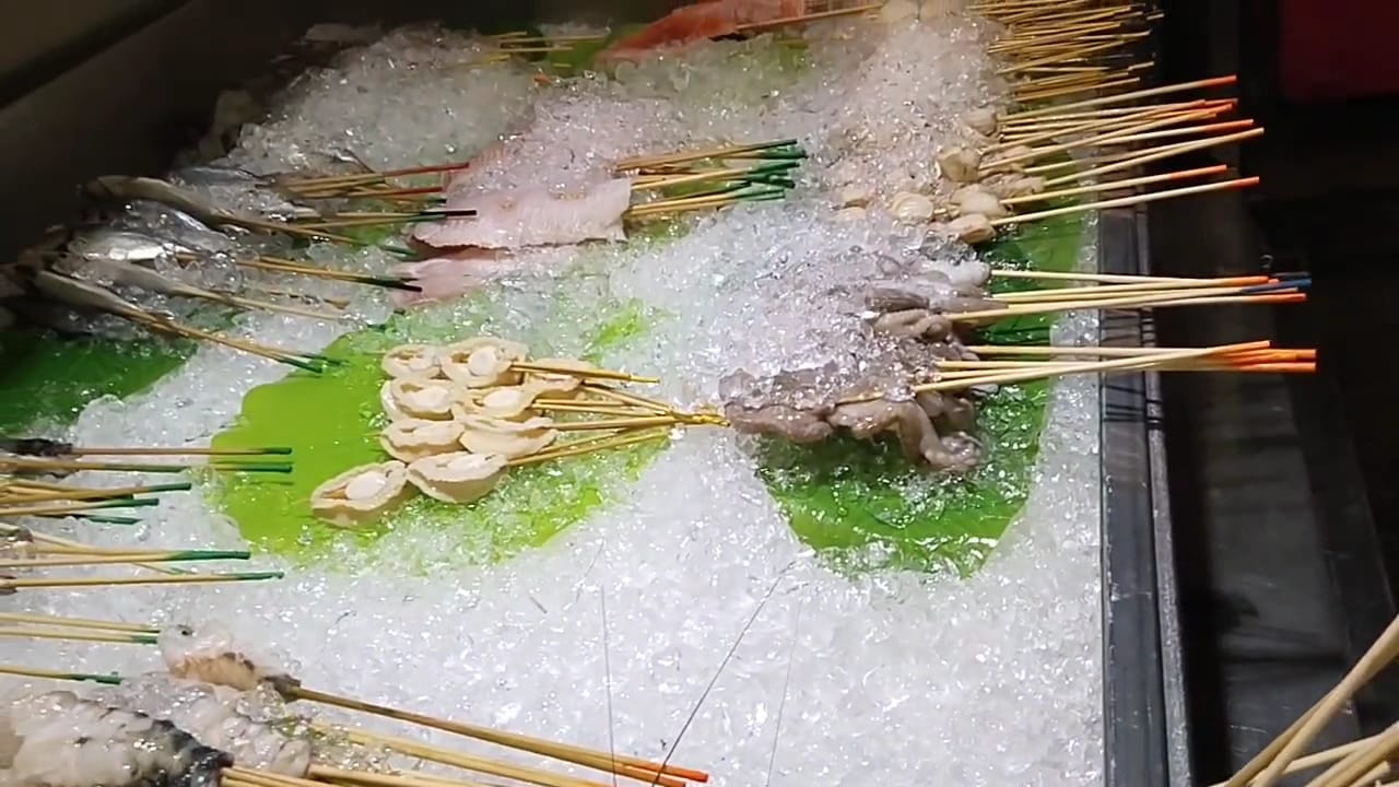 Raw seafood skewers — scallops, fish and octopus — laid on crushed ice and banana leaves